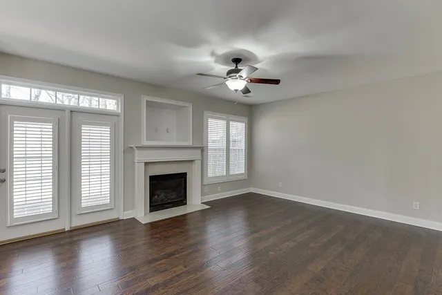 a view of an empty room with wooden floor fireplace and a window