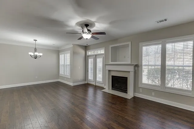 a view of an empty room with wooden floor fireplace and a window