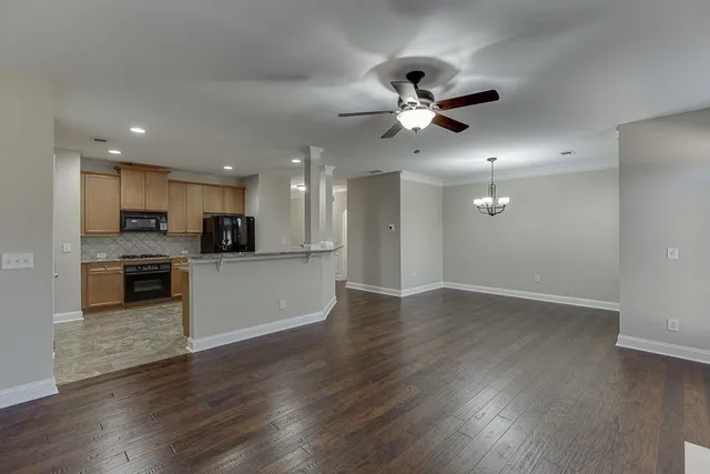 a view of an empty room with kitchen appliances and a ceiling fan