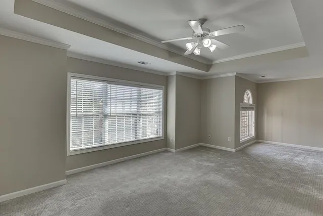 a view of an empty room with chandelier fan and windows