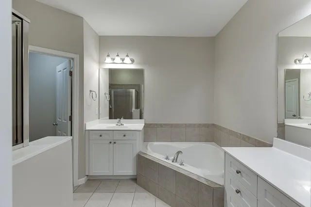 a bathroom with a tub a sink and mirror