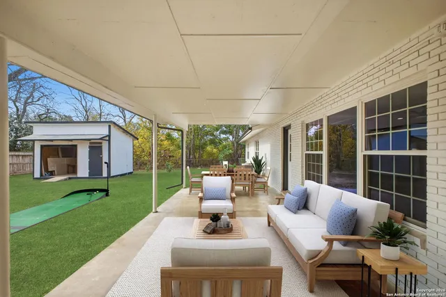 a view of a patio with couches dining table and chairs with wooden fence