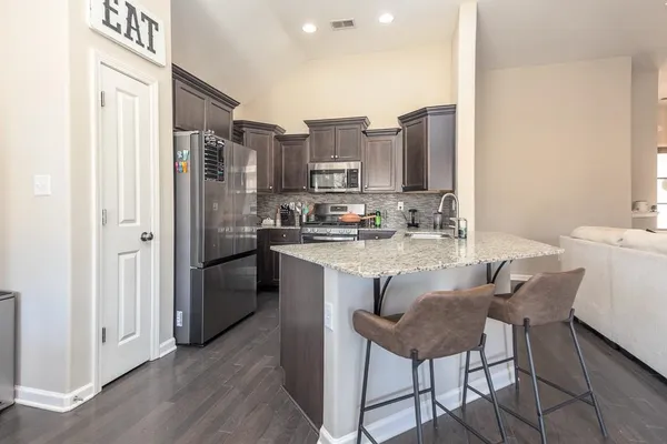 a kitchen with stainless steel appliances granite countertop a refrigerator and a stove top oven