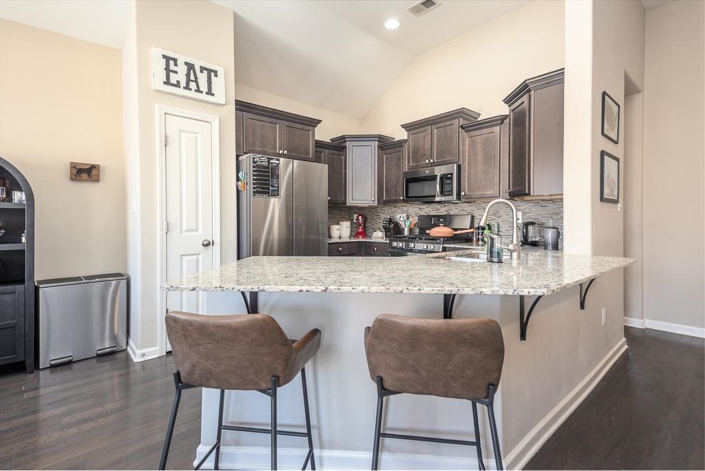 95 Chesnut Rdg Drive Oakland, TN 38060 - Photo 9 of 33 Kitchen with stainless steel appliances, dark wood finish cabinets, a peninsula, light stone counters, and dark wood finished floors