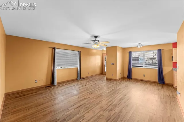 an empty room with wooden floor and windows