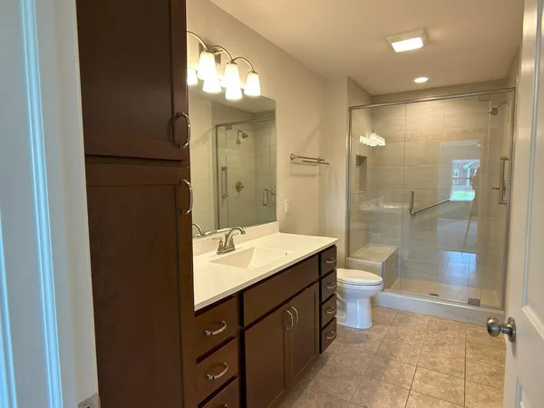 a bathroom with a double vanity sink toilet mirror and shower