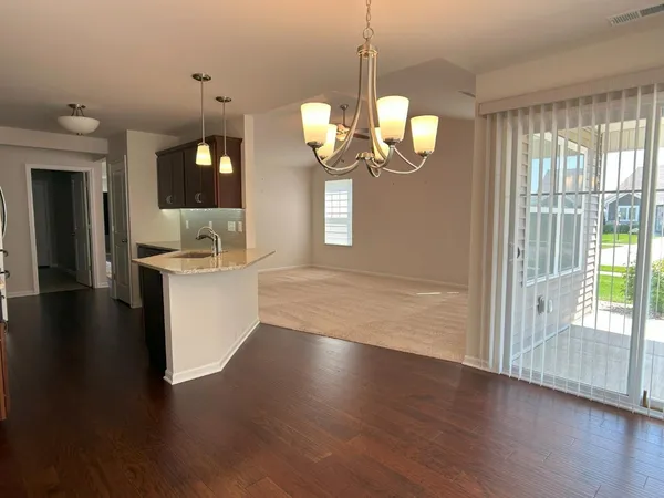 a view of a room with wooden floor chandelier and windows