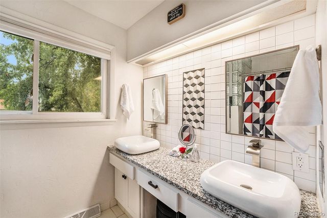 a bathroom with a granite countertop sink and a large mirror