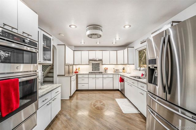 a kitchen with granite countertop a refrigerator stove top oven and sink