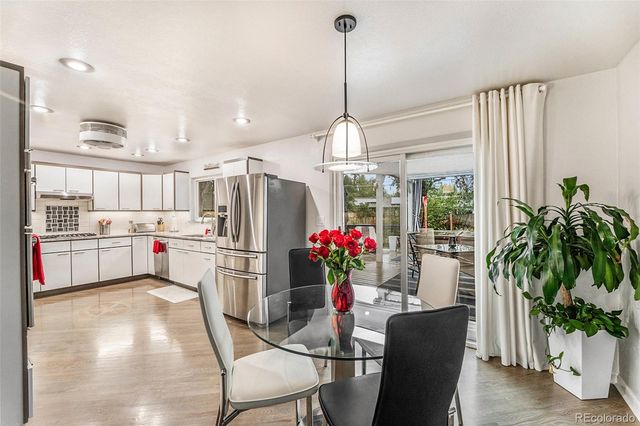 a kitchen with refrigerator and wooden floor