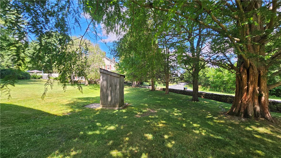 585 Buttermilk Road Hellertown, PA 18055 - Photo 60 of 82 A rustic storage shed nestles into a verdant lawn, framed by mature trees and a traditional stone wall.