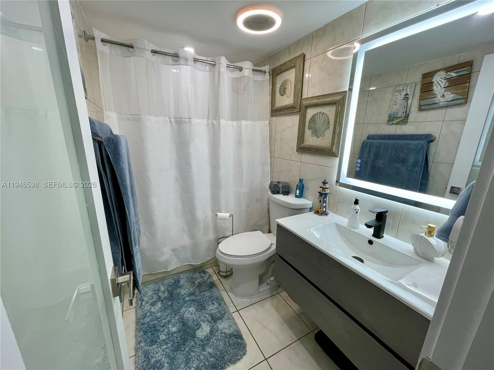 8635 Northwest 8th Street, Unit 311 Miami, FL 33126 - Photo 12 of 16 a bathroom with a sink a toilet a mirror a vanity and shower
