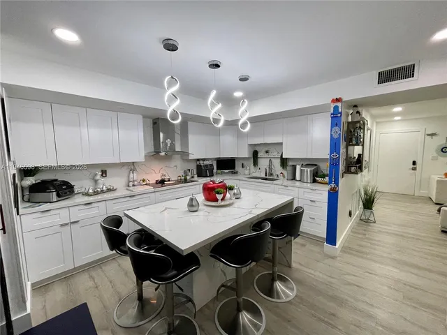 a kitchen with stainless steel appliances kitchen island granite countertop a table chairs in it and wooden floors