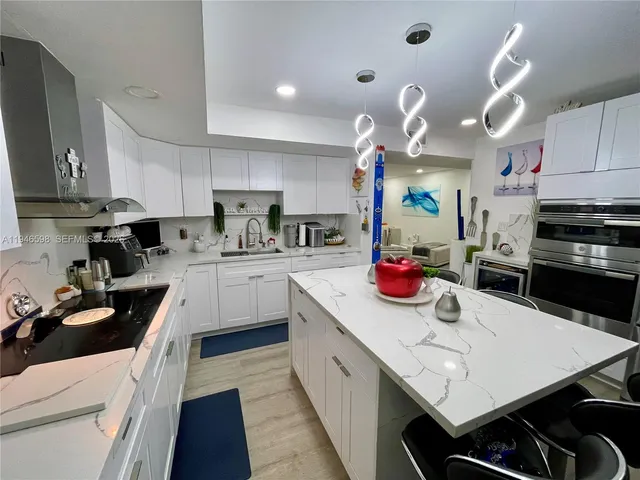 a kitchen with stainless steel appliances a sink a stove top oven a counter space and cabinets