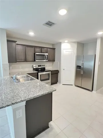 a kitchen with stainless steel appliances granite countertop a sink stove and refrigerator