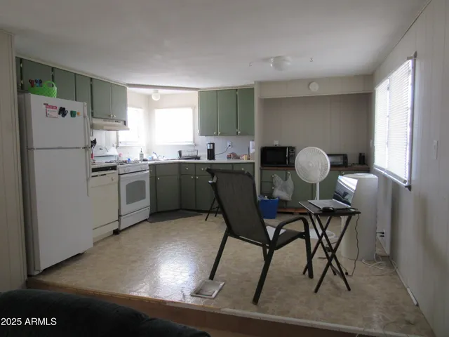 a kitchen with a table chairs refrigerator and window