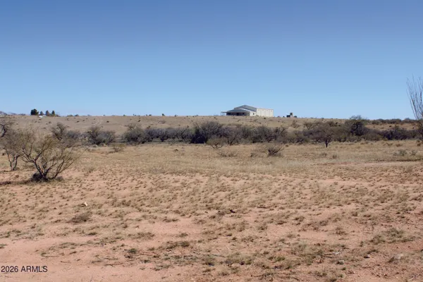 a view of a dry field with mountains in the background