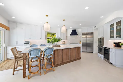 a kitchen with stainless steel appliances kitchen island granite countertop a table chairs and a refrigerator