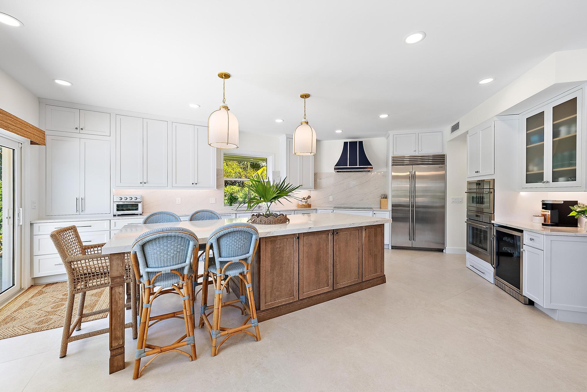 19 Island Road Sewall's Point, FL 34996 - Photo 10 of 50 a kitchen with stainless steel appliances kitchen island granite countertop a table chairs and a refrigerator