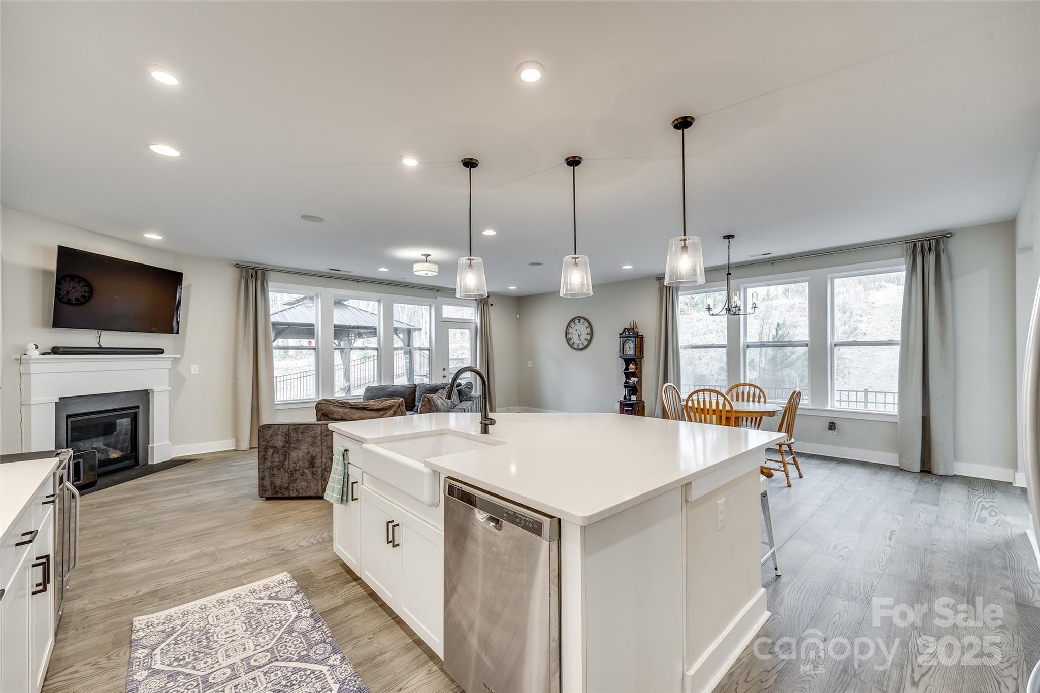 2024 Suttonview Road Fort Mill, SC 29708 - Photo 8 of 41 a large kitchen with kitchen island a stove a center island a sink dishwasher and a fireplace with wooden floor
