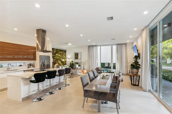 a living room with furniture kitchen view and large windows
