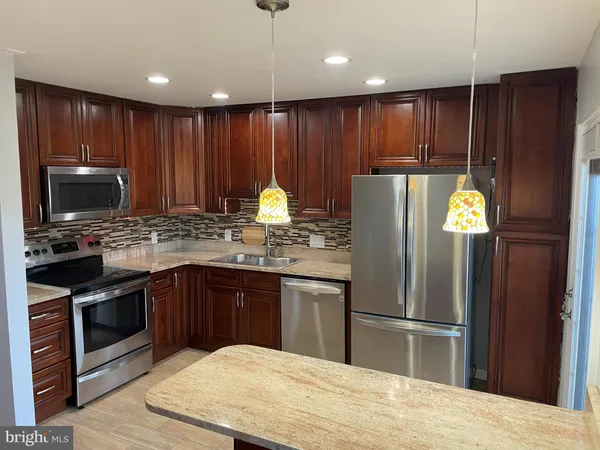 a kitchen with granite countertop stainless steel appliances a refrigerator microwave and stove