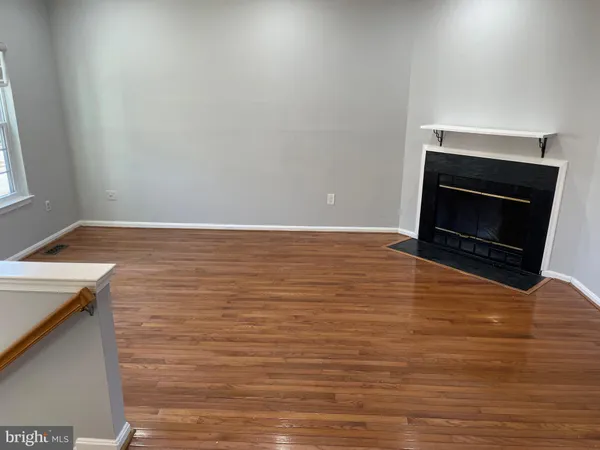 a view of an empty room with wooden floor and a fireplace