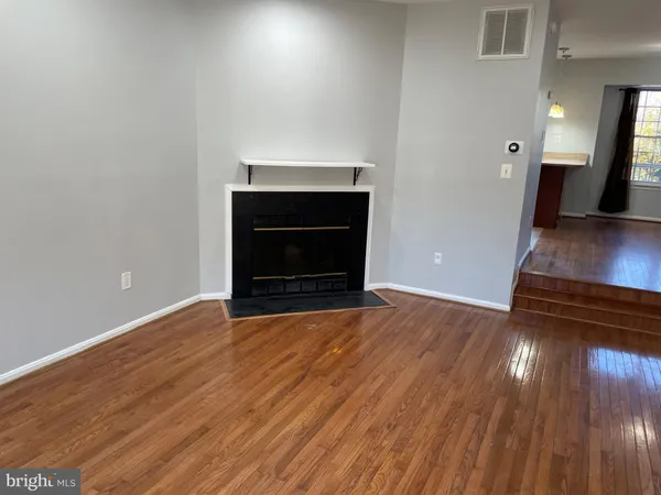 a view of an empty room with wooden floor and a fire place