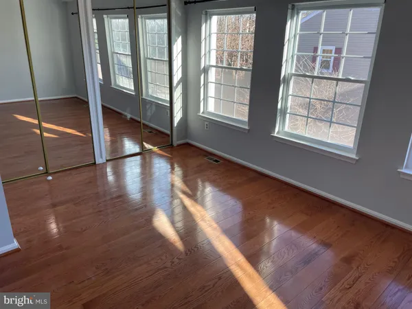 a view of an empty room with wooden floor and windows