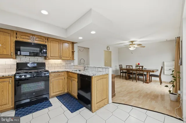 a kitchen with stainless steel appliances granite countertop a stove top oven a sink a dining table and chairs