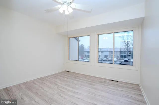 a view of an empty room with a window and wooden floor