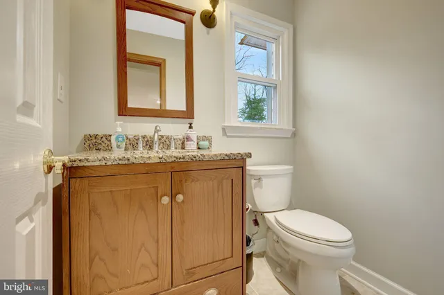 a bathroom with a granite countertop toilet sink and mirror