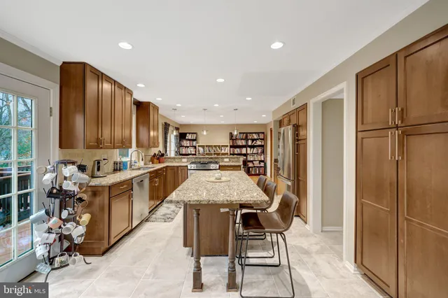 a kitchen with stainless steel appliances kitchen island granite countertop a refrigerator a stove a microwave oven with a dining table and chairs with wooden floor