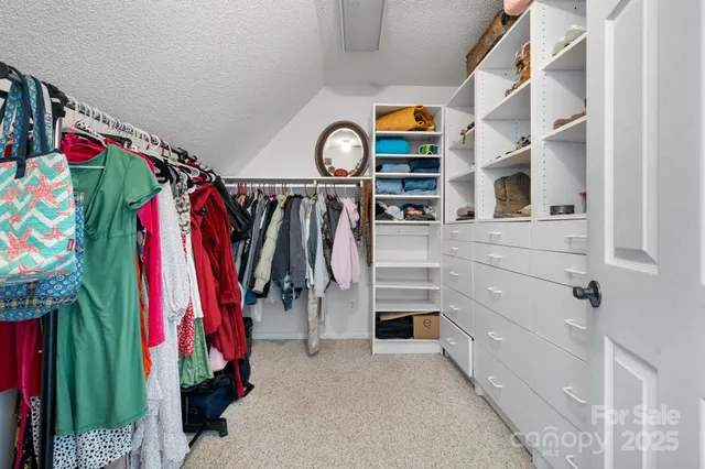 a view of walk in closet with clothes and shoes