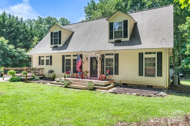 a view of house with a big yard and large trees