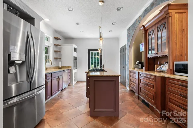 a kitchen with stainless steel appliances granite countertop a refrigerator a sink a stove and a refrigerator