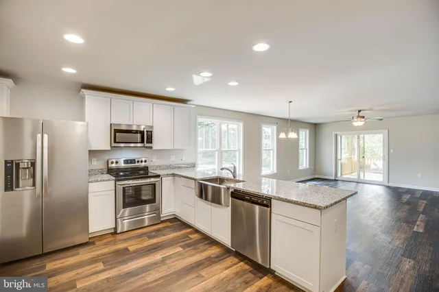 a large kitchen with granite countertop lots of counter top space and stainless steel appliances