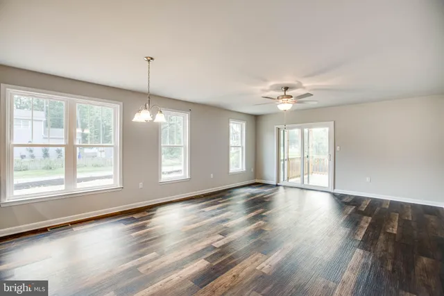 a view of an empty room with a kitchen and wooden floor
