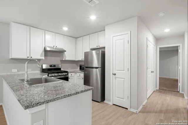 a kitchen with granite countertop a refrigerator and a sink