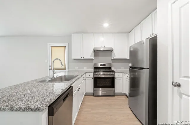 a kitchen with stainless steel appliances granite countertop a refrigerator a sink and a stove