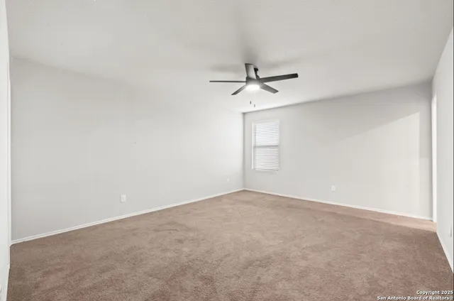 an empty room with a window and a ceiling fan