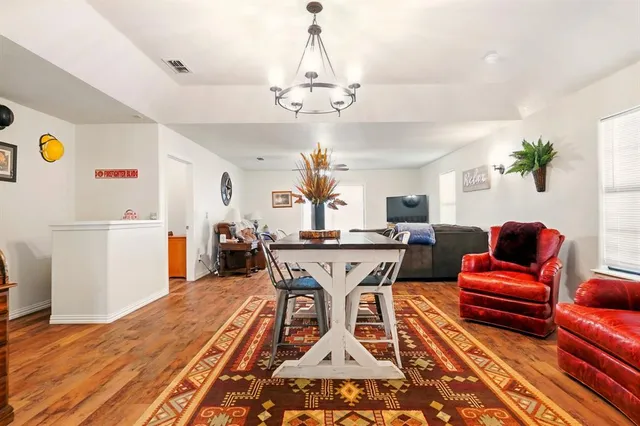 a living room with dining table a rug and a chandelier