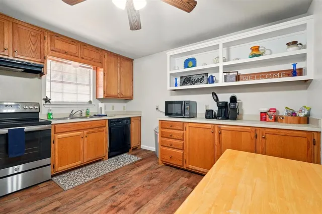 a kitchen with stainless steel appliances granite countertop a sink dishwasher stove and cabinets with wooden floor