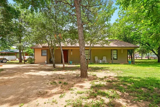 a front view of a house with a garden and trees