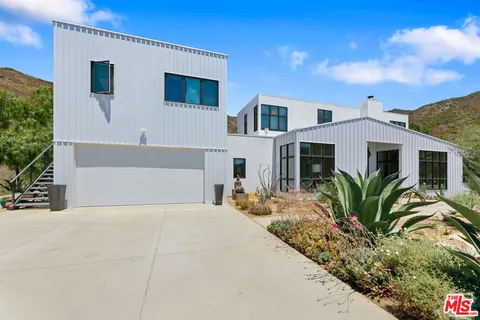 a front view of a house with a yard and mountain view