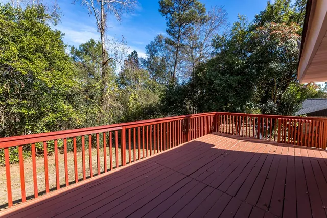 a balcony with wooden floor and trees in the back