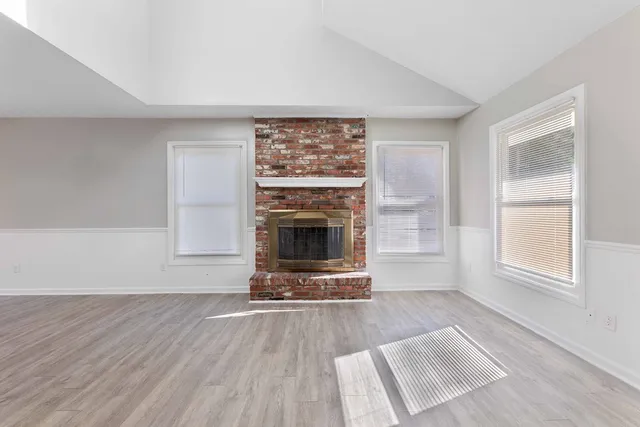 a view of a livingroom with wooden floor a fireplace and windows