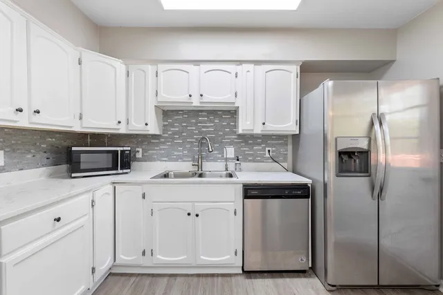a kitchen with white cabinets and stainless steel appliances