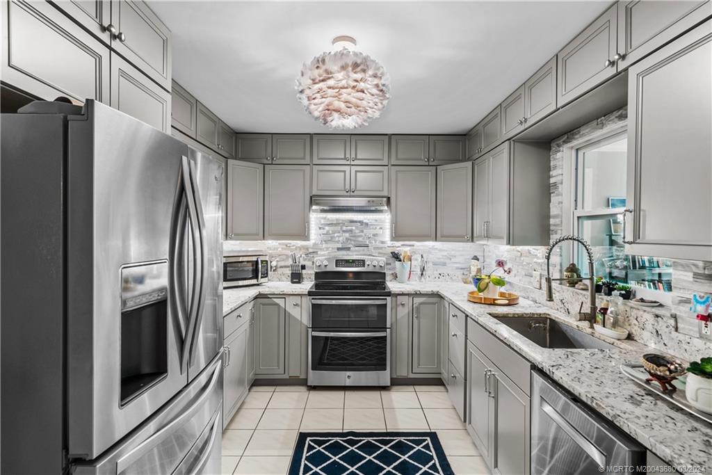 9182 Southeast Apollo Street Hobe Sound, FL 33455 - Photo 9 of 26 a kitchen with stainless steel appliances a stove a refrigerator and a sink
