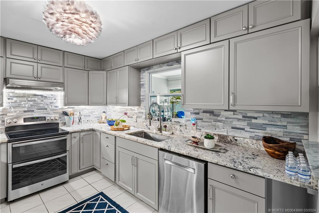 9182 Southeast Apollo Street Hobe Sound, FL 33455 - Photo 10 of 26 a kitchen with stainless steel appliances a sink stove and cabinets